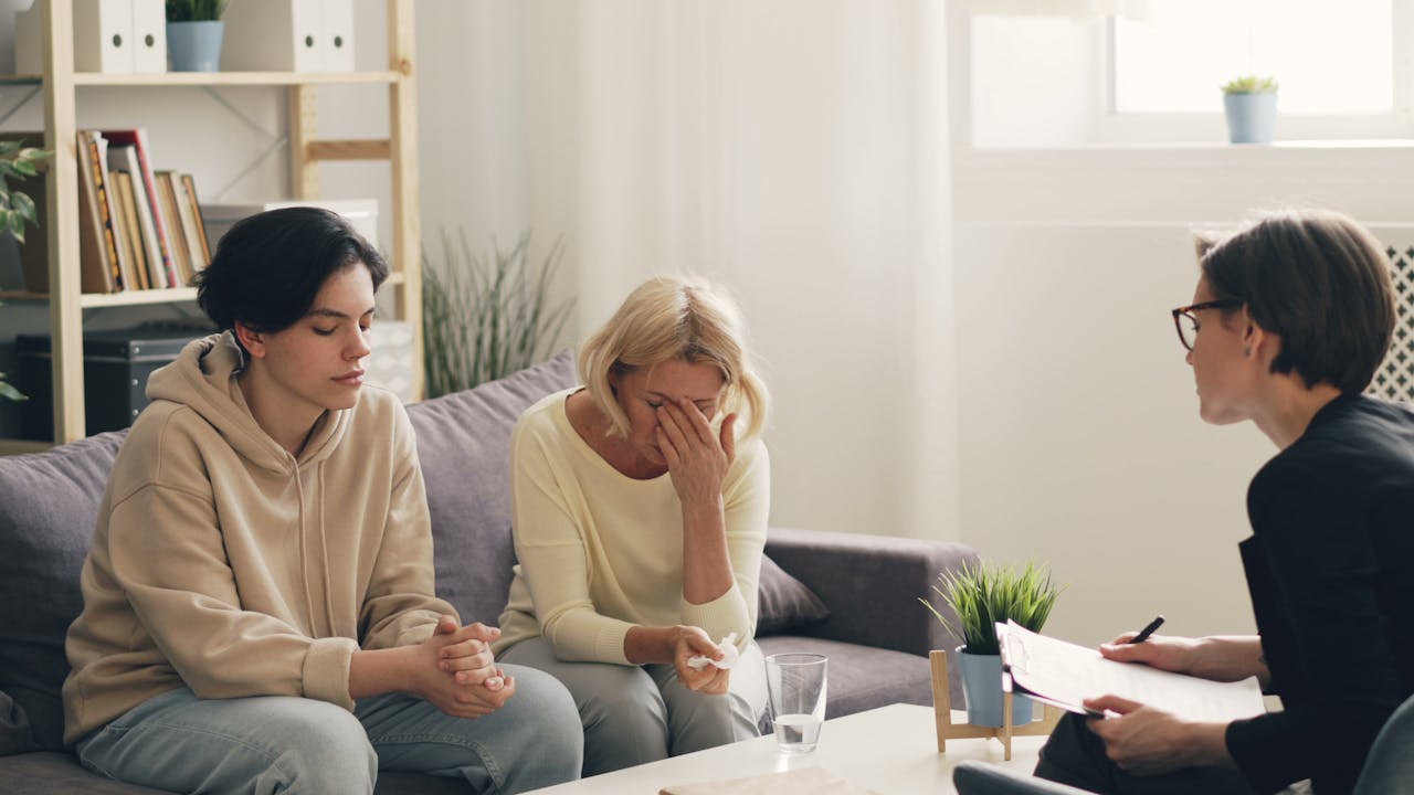 three women sitting on a couch talking to each other 23495757